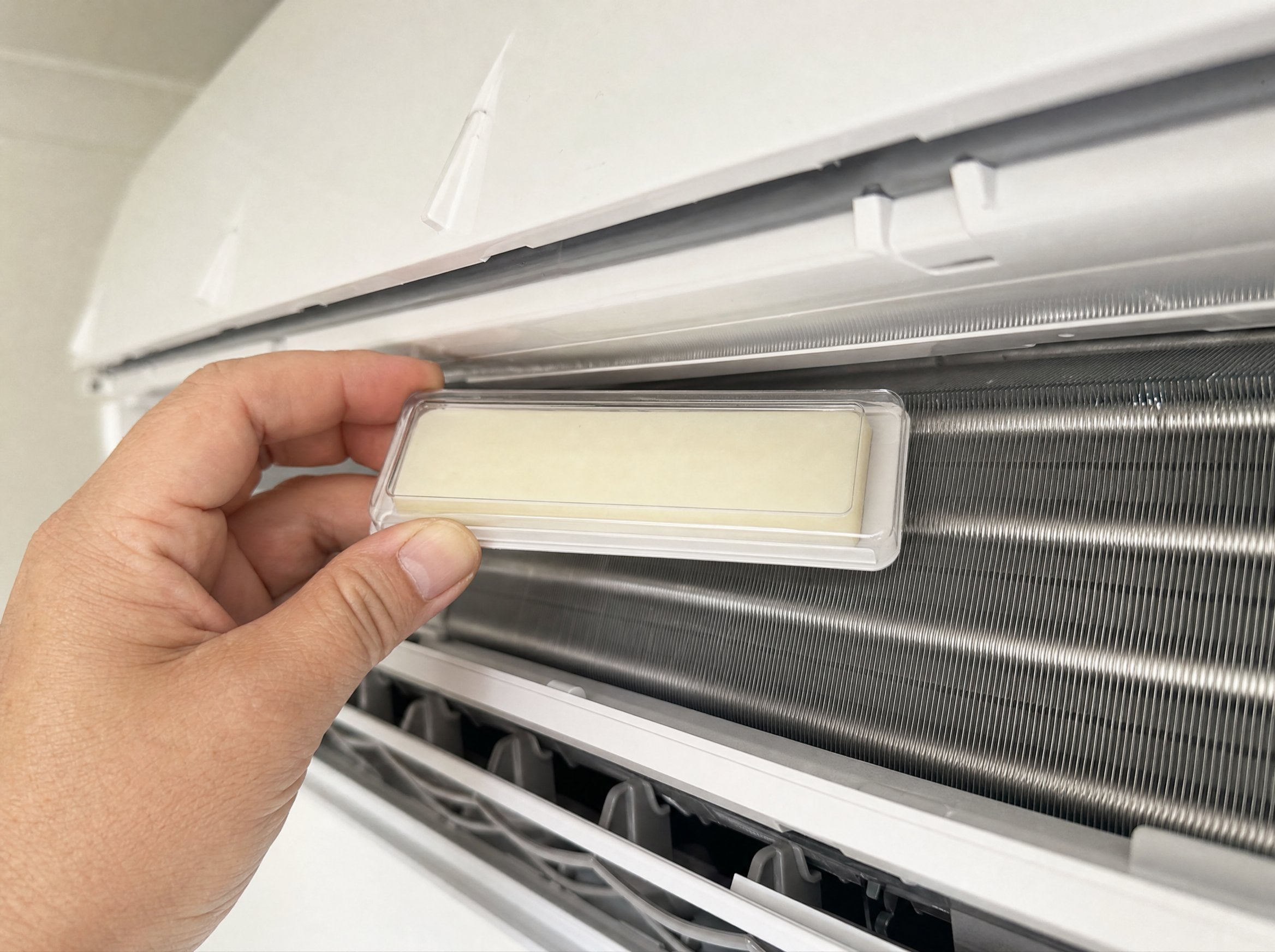 Hand placing the anti-mould diffuser inside an opened split-system aircon